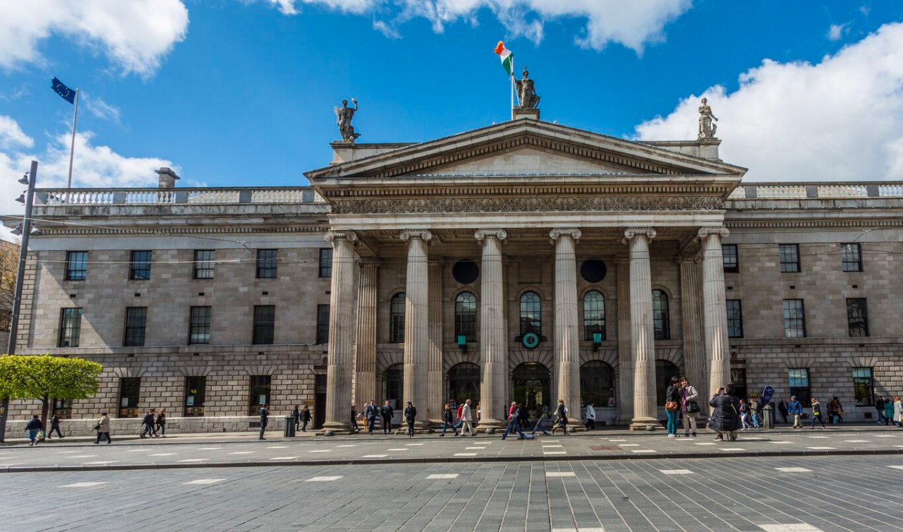 Traffic free O'Connell Street with pedestrians outside General Post Office on sunny day with blue sky